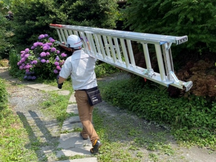 調査の為に三連梯子を肩で担ぐ作業員