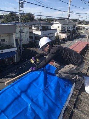 パラペット笠木の飛散部にブルーシートで応急処置する店長