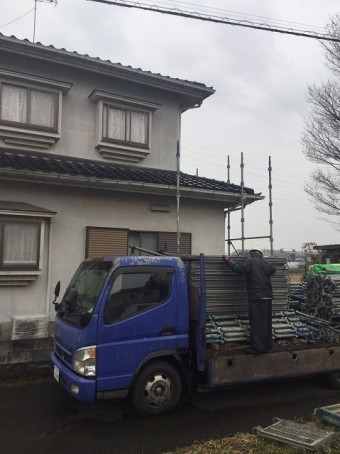 トラックの荷台から足場材を降ろす作業員