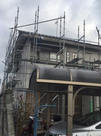 組み上がった足場で雨樋の交換作業を行う作業員