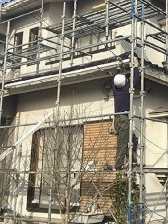 1階の軒に新しい軒樋を施工する職人