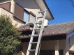 屋根に登り瓦下を覗き込む作業員