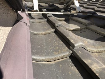瓦屋根の上にエアコンの室外機の架台が設置されている