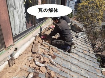 壁際の瓦を解体する職人