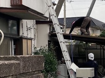 自転車小屋の屋根をつたう職人