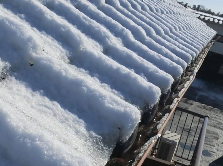屋根に積雪し軒樋に溶けた雪が溜まっている