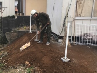 盛り土を行い、道具を使用して土台を叩き固める職人
