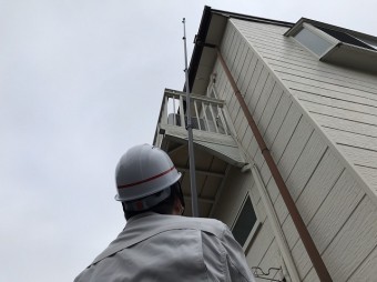 高所棒を伸ばし屋根の状態を撮影するスタッフ