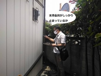 雨樋支持金具がしっかり止まっているかを確認するスタッフ