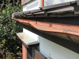 赤茶色の半丸雨樋が変形している