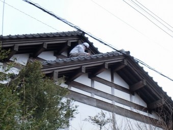 雨漏り箇所を特定する為屋根に登り部位を覗き込む調査員