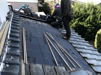瓦屋根の部分葺き直し作業中の職人