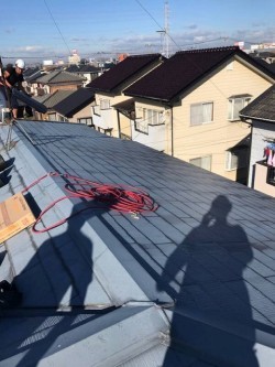 屋根に荷物を揚げる職人
