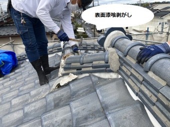 棟の表面に塗布された漆喰を剥がす職人