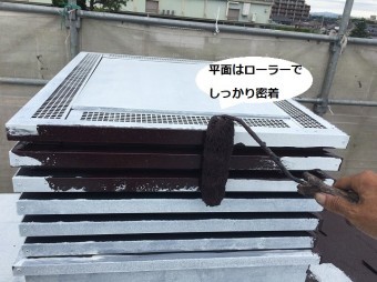 換気用煙突にローラーで遮熱塗料を塗布する職人