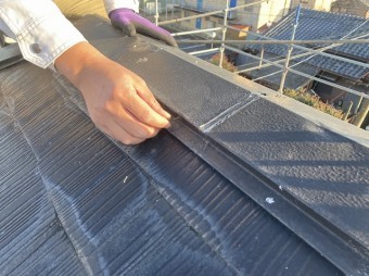 棟板金から抜けかかった釘をつまむスタッフ