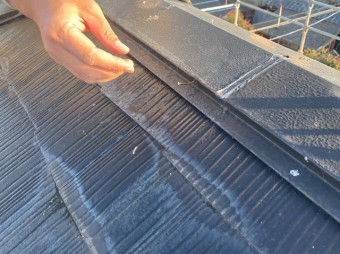 抜け掛かっている棟板金の釘を手で触れようとするスタッフ