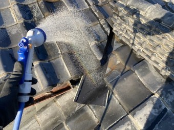 シャワーホースで谷板金に散水を行う様子