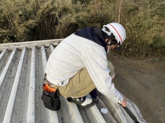 折板屋根の穴をパテで埋める職人