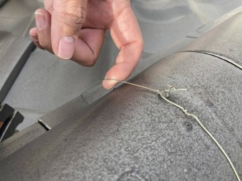 棟瓦の銅線の緩みを確認するスタッフ