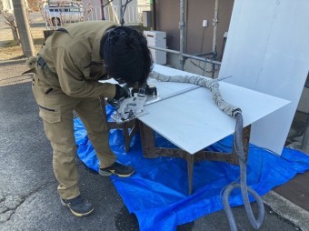 電動丸ノコで軒天材を切断する職人