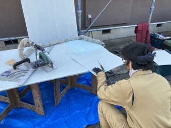 ノコギリで軒天材を切断する職人
