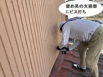 外壁トタンの留め具欠損部にビスを打つ作業員