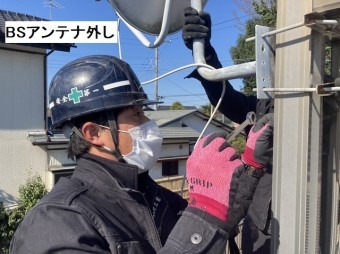 ベランダ手すりに設置されたBSアンテナを撤去する作業員