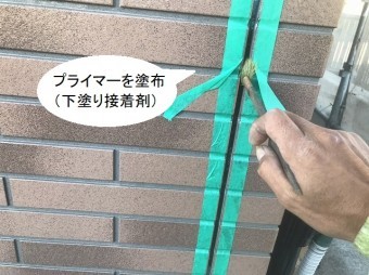サイディングの目地に接着プライマーを塗布する職人