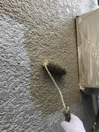 右手でプレミアムシリコン塗料をぬっています