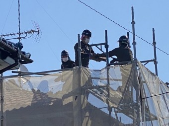 2階の屋根部で解体した瓦をバケツリレーする縮人