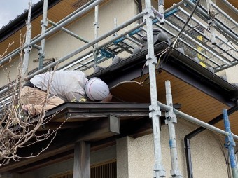玄関軒先屋根から施工部位を覗き込みながら最終チェックする店長
