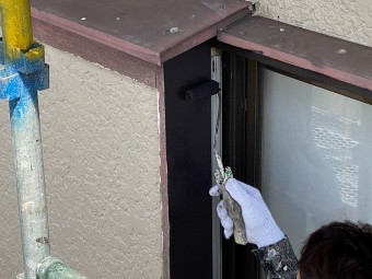 ローラーを使い茶色の塗料を戸袋に塗布する職人