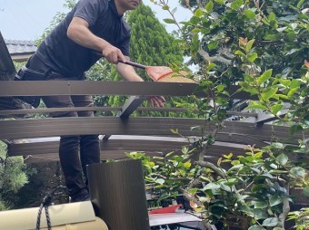 脚立に乗り、カーポートアルミ枠の清掃を行う職人