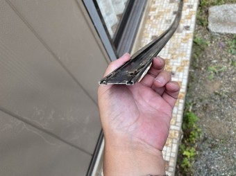 手元に持ちカーポートパネルの押さえ材パッキン劣化を確認するスタッフ