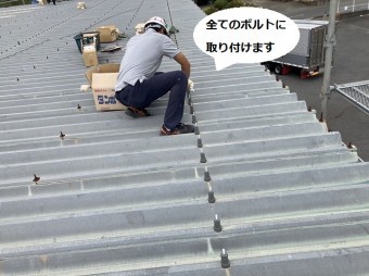 一列に並ぶボルトに金具を取り付けていくスタッフ