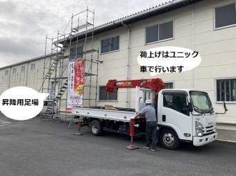 荷揚げ用のユニック車と作業員が登り下りする昇降足場