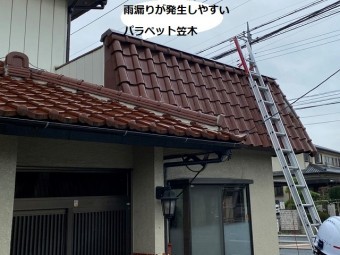 パラペット屋根に二連梯子を掛けるスタッフ