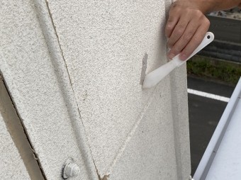 白いへらで外壁のクラックに変成シリコンをのばすスタッフ