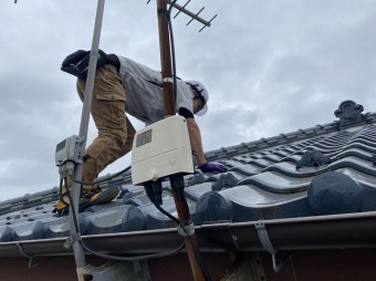 四つん這いになりながら瓦屋根を上るスタッフ