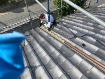 大きな下屋根に這樋を施工する為に計測する職人