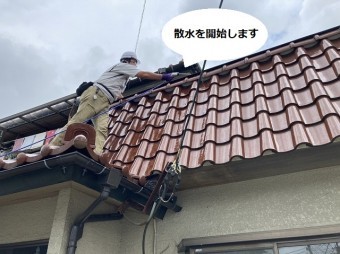パラペット笠木の下から散水を開始するスタッフ