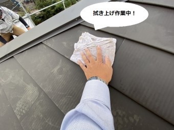 屋根の上で板金屋根を葺き上げ清掃するスタッフ