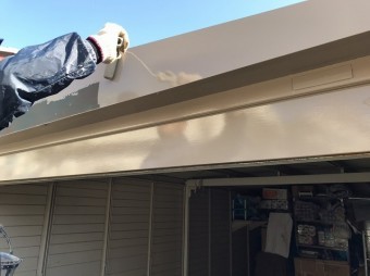 車庫の凹凸部へローラーで塗装を行う職人