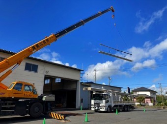 桜川市の屋根カバー工法で使用する折板屋根をクレーンで吊っている場面