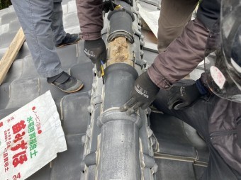 棟瓦のラバ―ロックをカッターで撤去する職人