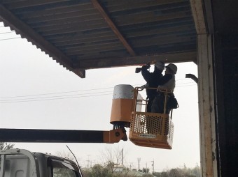 高所作業車で既存の雨樋をサンダーで切断する作業員