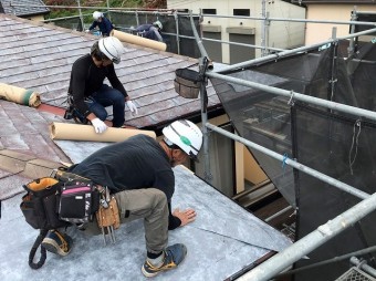 スレート屋根材に粘着防水シートを施工する複数の職人