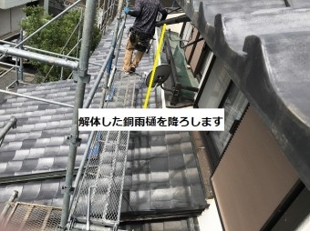 解体した銅軒樋を2階から1階に降ろしている職人