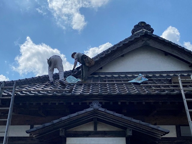 入母屋根屋根で作業を行う二名の職人